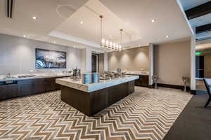 Kitchen featuring recessed lighting, light stone counters, pendant lighting, dark brown cabinetry, and a spacious island
