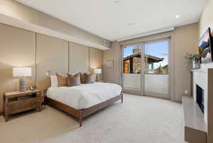 Bedroom featuring access to outside, carpet flooring, and a fireplace with raised hearth