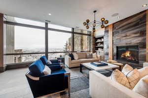 Living area with a high end fireplace, a chandelier, built in features, expansive windows, and recessed lighting