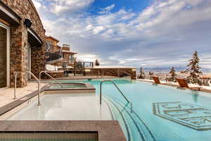 Community pool with a hot tub, a balcony, a patio, and a mountain view