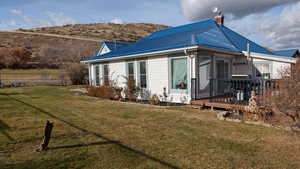Rear view of house featuring a metal roof, a wooden deck, and a chimney. View looking Northwest.