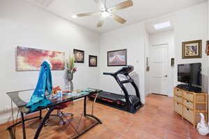 Office space featuring light tile patterned floors, ceiling fan, and a skylight