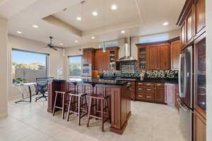 Kitchen with a breakfast bar area, glass insert cabinets, a kitchen island, pendant lighting, and brown cabinetry