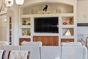 Living area with built in features and a chandelier