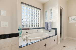 Full bathroom featuring a bath and light tile patterned floors
