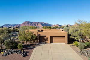 Adobe home with a mountain view, stucco siding, an attached garage, and driveway
