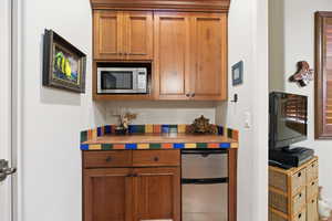 Kitchen with appliances with stainless steel finishes, brown cabinetry, and tile counters