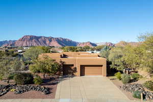 View of front of property featuring stucco siding, a mountain view, concrete driveway, and a garage