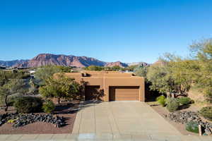 Adobe home featuring a mountain view, stucco siding, an attached garage, and driveway