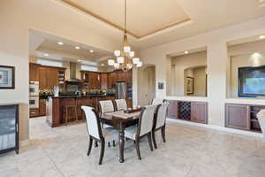 Dining room featuring a raised ceiling, arched walkways, a chandelier, recessed lighting, and beverage cooler