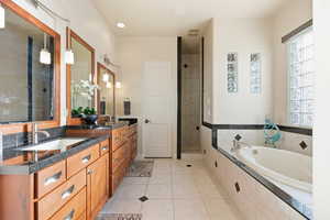 Full bath featuring a bath, double vanity, light tile patterned floors, and walk in shower