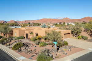 Pueblo revival-style home with a mountain view, stucco siding, and concrete driveway
