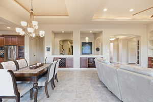 Dining area with arched walkways, built in shelves, recessed lighting, a tray ceiling, and a chandelier