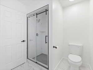 Bathroom with marble finish floors and a stall shower
