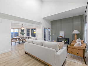 Living area featuring light wood-style floors, a high ceiling, and a decorative wall
