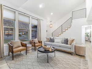 Living area featuring light wood finished floors, a chandelier, stairs, and recessed lighting