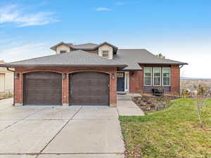 View of front of property featuring a front yard, a shingled roof, driveway, an attached garage, and brick siding