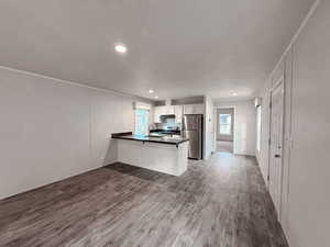 Kitchen featuring a peninsula, dark countertops, dark wood-type flooring, appliances with stainless steel finishes, and recessed lighting
