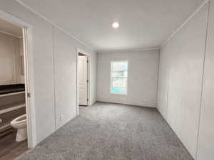 Unfurnished bedroom with crown molding, carpet flooring, and ensuite bath