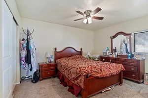 Bedroom featuring light carpet, a ceiling fan, a closet, and a textured ceiling