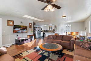 Living room featuring a textured ceiling, wood finished floors, ceiling fan, and a chandelier
