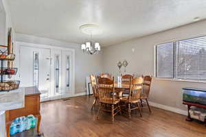 Dining area with a textured ceiling, wood finished floors, and a chandelier