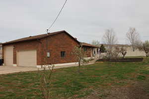 View of home's exterior with brick siding, a garage, a lawn, and driveway