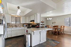 Kitchen with pendant lighting, white cabinets, light countertops, stainless steel fridge with ice dispenser, and a textured ceiling