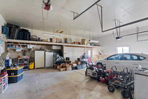 Garage featuring white fridge, freestanding refrigerator, and a garage door opener