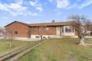 Back of house featuring brick siding, a lawn, and a chimney