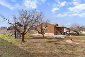 View of home's exterior with a patio area, brick siding, a yard, and a playground