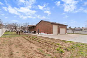View of home's exterior featuring brick siding, a patio area, and driveway