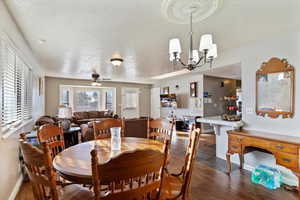 Dining room with dark wood-style flooring, a textured ceiling, ceiling fan, and a chandelier