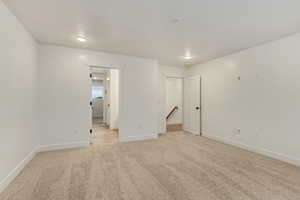 Unfurnished room featuring light carpet and baseboards