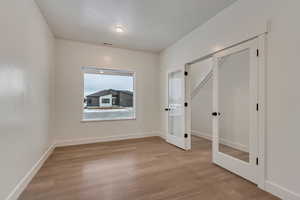 Unfurnished bedroom featuring light wood-style floors and french doors