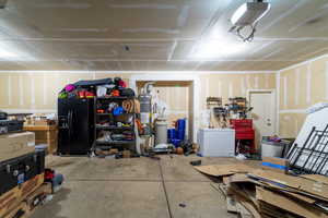 Garage featuring black refrigerator with ice dispenser, a workshop area, secured water heater, and a garage door opener
