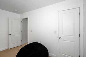 Living area with baseboards and light carpet