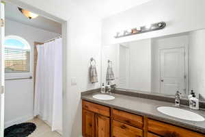 Bathroom featuring a shower with shower curtain and double vanity