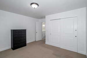 Unfurnished bedroom featuring light carpet and a closet