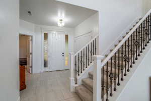 Foyer with stairs and light tile patterned floors