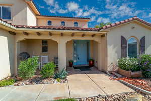 View of exterior entry with stucco siding, a tiled roof, and a porch