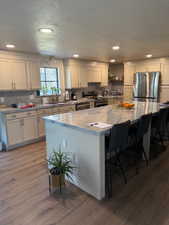 Kitchen with recessed lighting, stainless steel appliances, a textured ceiling, a large island, and dark wood-style floors