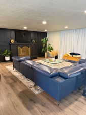 Living area featuring light wood-type flooring, a decorative wall, recessed lighting, and a textured ceiling