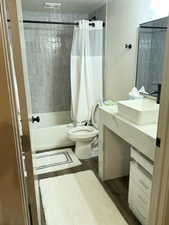 Bathroom with vanity, shower / tub combo with curtain, and dark wood-style floors