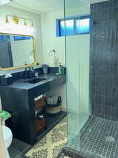 Full bath featuring vanity, dark tile patterned floors, a tile shower, and a textured ceiling