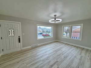 Foyer entrance featuring a textured ceiling and light wood finished floors