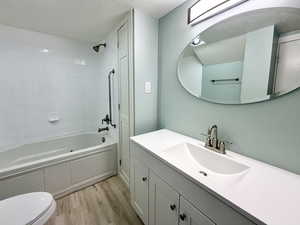 Bathroom with  shower combination, a textured ceiling, vanity, and light wood-style flooring