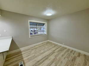 Unfurnished dining area featuring a textured ceiling and light wood-style flooring