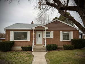 Bungalow-style home featuring a front yard, a chimney, and brick siding