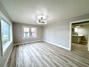 Unfurnished room with a textured ceiling and light wood finished floors